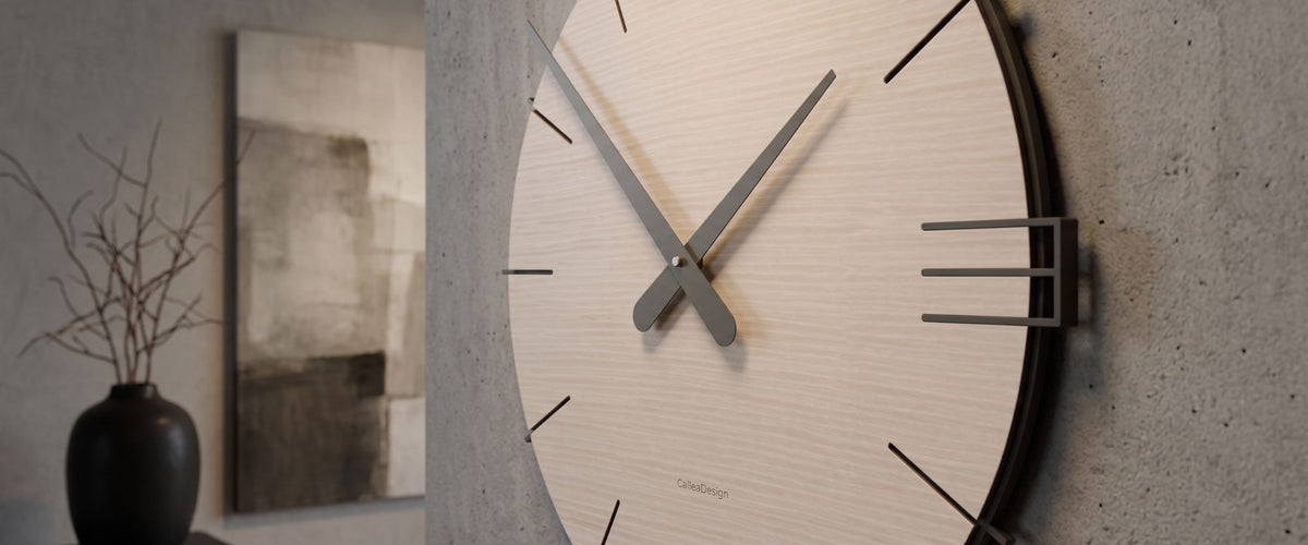 Close-up of a CalleaDesign wall clock with a light wood dial and dark hands in a contemporary interior