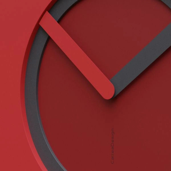 Close-up of the KAM Lava wall clock with a red dial, dark circular ring and contrasting hands